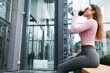 Fototapeta Sypialnia - Young fitness woman with a beautiful figure drinks from a shaker
