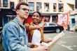 © BullRun - African American young woman inhabitant of city pointing hand on right direction to help Caucasian tourist with map to find destination, friends standing on street and searching showplace in town