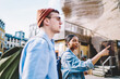 © BullRun - African american young woman pointing right direction while walking in urban setting together with hipster guy during weekend's trip.Diverse couple in love dressed in casual wear talking about route