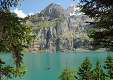 A Tiny Rower On The Oeschinensee Dwarfed By The Surrounding Mountains.