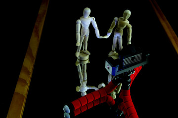 Miniature photo set with two wooden mannequins. The surface of the scene is a mirror.