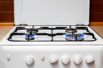 Close-up kitchen white gas stove on a countertop with two burning lights