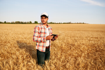 Precision farming. Farmer holding tablet pc, using online data management software at wheat field. Agronomist working with touch computer screen, control, analyse agriculture business. Innovative tech