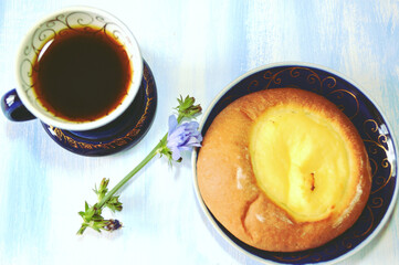 Chicory caffeine-free drink in blue cup, chicory flower and cheese pastry on the light-blue wooden table. Food still life.  Healthy breakfast. Good morning. 