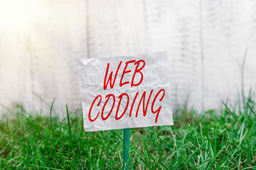 Fototapete - Conceptual hand writing showing Web Coding. Concept meaning a system of symbols and rules used to represent instructions Plain paper attached to stick and placed in the grassy land