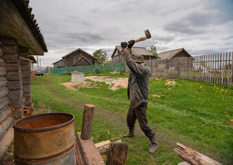 an elderly man is chopping wood with an axe