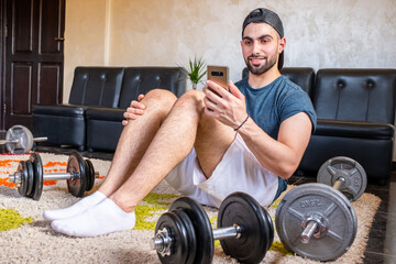 Wall Mural - Athletic guy learing weight lfting using video tutorials