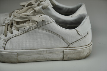 Dirty, used, muddy white dirty pair of shoes on white dirty floor