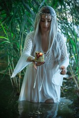 Mermaid girl bride in white dress in lake. Fantasy girl. Mysterious scene. Witch standing in the river and practice witchcraft. Fairytale