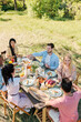 © pressmaster - Six young friends of various ethnicities gathered by served table for dinner