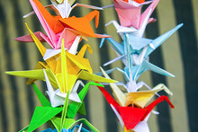 Origami Festive Garland Outdoor. Abstract Background. Origami Paper Handmade. Multicolored Rainbow Origami Paper Cranes Are Suspended On Gradient Near The Garland.colorful Paper Origami Birds.