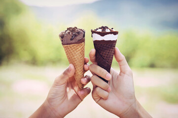 two hand holding ice cream cone in nature background