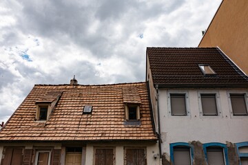 Sticker - Two houses with a wooden and modern roof under a cloudy sky