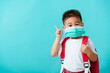 © sorapop - Back to school coronavirus Covid-19 education. Portrait Asian cute little child boy kindergarten wear face mask protective and school bag pointing finger to side, studio shot isolated blue background