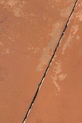 Wall Mural - Vertical shot of a crack inside the brown wall