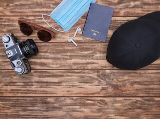 Canvas Print - Top view of a camera, sunglasses, mask, passport, ear pads and hat on a wooden background