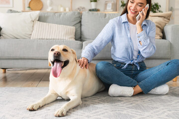 Wall Mural - Portrait of young woman with her dog using mobile