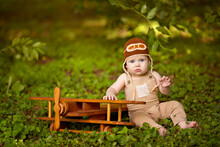 Happy Little Infant Boy Of 8-12 Months Old Is Flying On A Plane In Nature. Baby Pilot