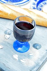 Poster - High angle closeup shot of a glass of red wine on a table next to seashells in front of baguette