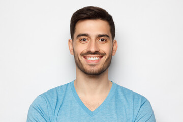 Portrait of young handsome smiling man, wearing casual blue t-shirt, isolated on gray background