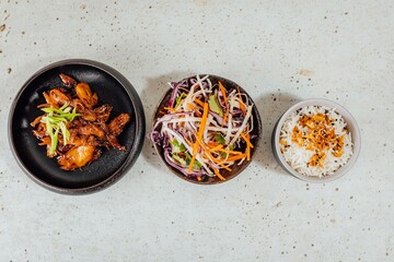 Wall Mural - Top view of a bowl of vegetables, white rice, and meat on a white table