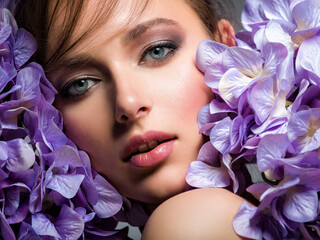 Wall Mural - Pretty woman with bright makeup. Beautiful white girl with flowers. Stunning brunette girl with big bouquet  of hydrangeas. Closeup face of young beautiful woman with a healthy clean skin.