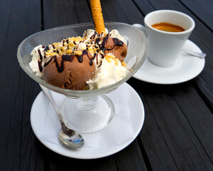  Ice cream and a white cup with hot coffee on a black wooden table.