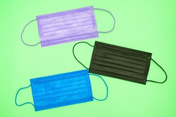 Poster - High angle shot of purple, black and blue medical face masks on a green surface