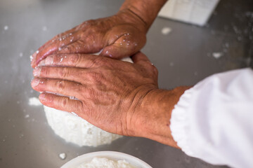  Man kneads the whey from the curd to make ricotta cheese in a small cheese factory in Italy