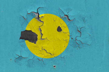 Palau flag close up old, damaged and dirty on wall peeling off paint to see inside surface. Vintage National Concept.