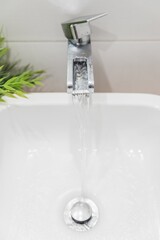 Canvas Print - Water running  from the modern styled faucet in the sink