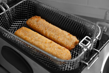 Wall Mural - Fish fingers in a mesh basket,  cooked in an electric deep fat fryer appliance.  Fast food concept