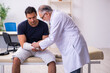© Elnur - Young injured man visiting experienced male doctor traumatologis