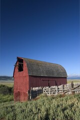 Canvas Print - Old red wooden building in Montana USA with roof in form of arc and a fence around