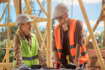 two engineers discuss the construction process according to a drawing against the background of a construction tower crane