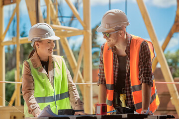 two engineers discuss the construction process according to a drawing against the background of a construction tower crane