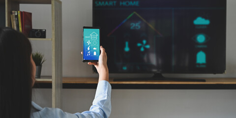 A young woman is using a smartphone with a controlled application. Smart home concept.