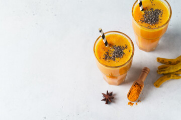 Wall Mural - Turmeric smoothie in glass with ingredients, powder, ginger and spice on white or light grey background