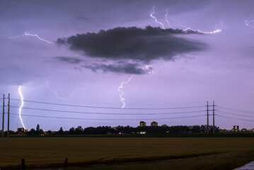 Wall Mural - lightning bolts strike down near power lines during a stormy night