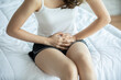 © 220 Selfmade studio - woman have bladder pain and stomach ache sitting on bed