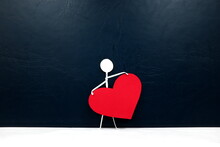 Human Stick Figure Holding A Big Red Heart In Dark Background. Give Love And Solo Valentines Day Celebration Concept.