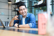 © chayathon2000 - Young Asian Man in blue shirt working with laptop in coffee shop cafe smile and happy face