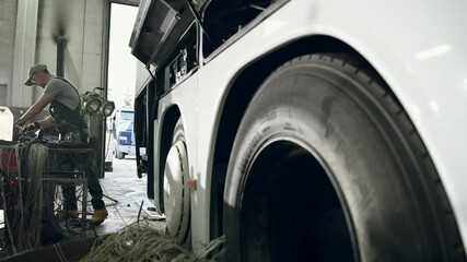 Wall Mural - Auto Technician Standing At Workbench Of Auto Repair Shop Choosing Tools To Fix Broken Coach Bus. 