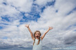 Little girl having fun against sky clouds outdoors