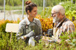 © Seventyfour - Side view portrait of cheerful young woman talking to senior farmer while working at plantation in sunlight, copy space