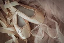A Pair Of Pink Satin Pointe Ballet Shoes With Tulle On A Vintage Chair