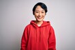 © Krakenimages.com - Young beautiful asian girl wearing casual sweatshirt with hoodie over white background with a happy and cool smile on face. Lucky person.