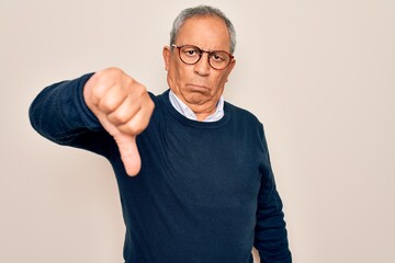 Wall Mural - Senior handsome grey-haired man wearing sweater and glasses over isolated white background looking unhappy and angry showing rejection and negative with thumbs down gesture. Bad expression.