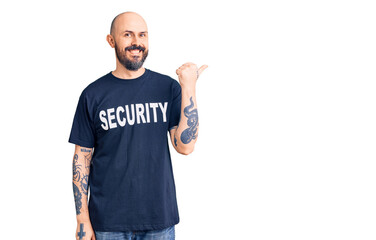 Poster - Young handsome man wearing security t shirt pointing to the back behind with hand and thumbs up, smiling confident