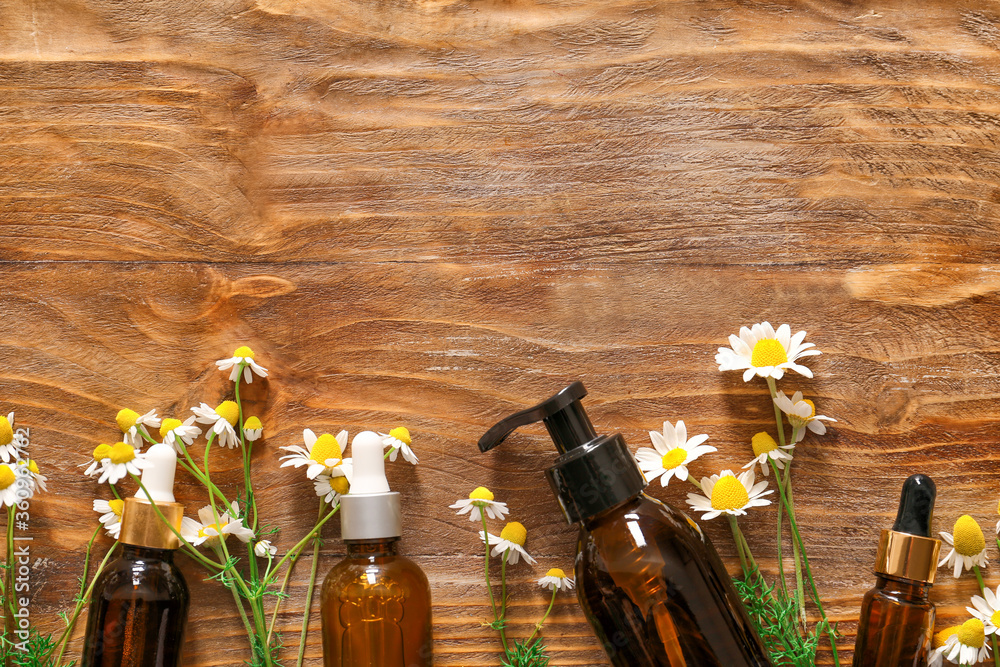 Cosmetics with chamomile flowers on wooden background